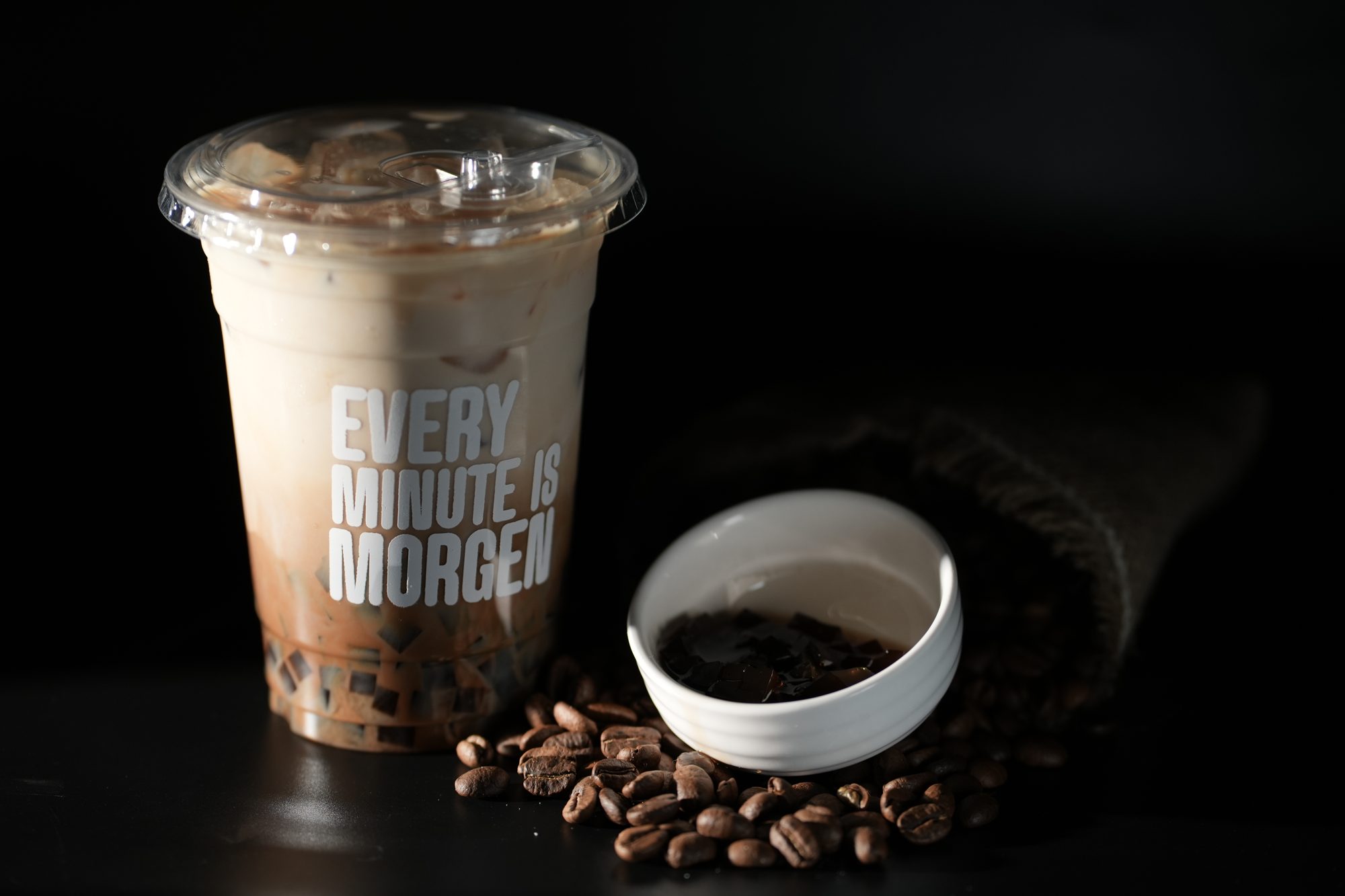 An iced Morgen latte beside a bowl of freshly roasted beans