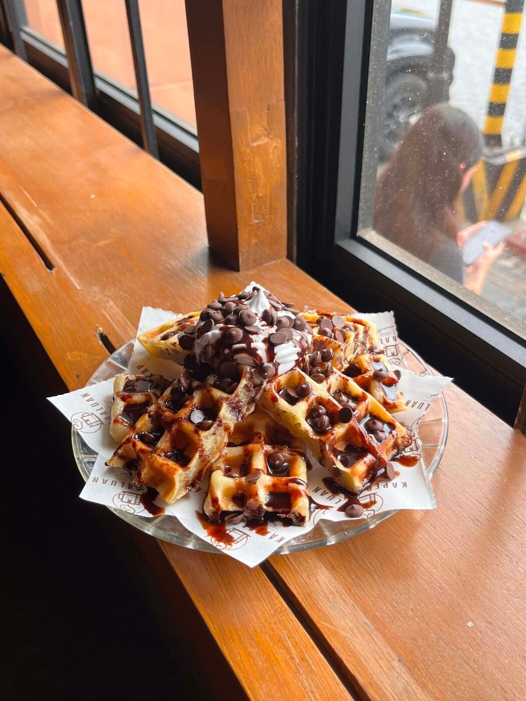 A plate of chocolate chip waffles with whipped cream