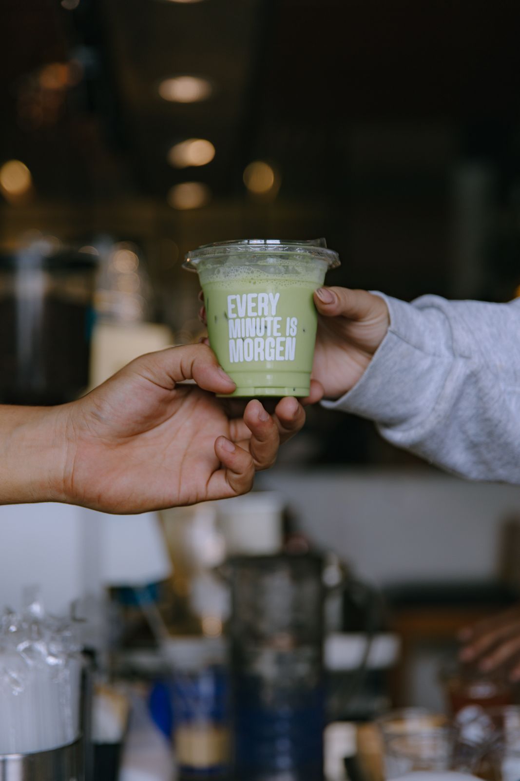 A barista handing over an iced matcha latte